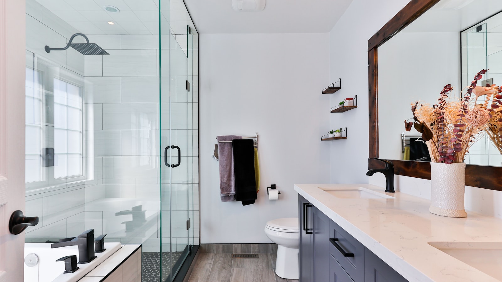 A finished modern bathroom with white subway tile shower and a dark wood vanity