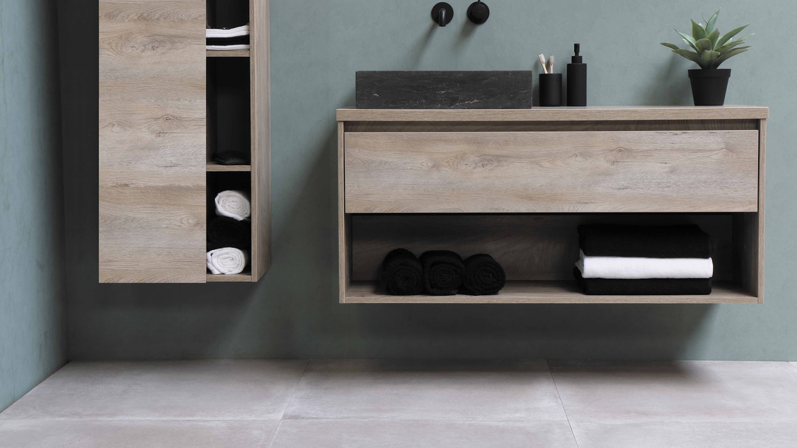 An oak vanity against a soft sage wall with folded towels
